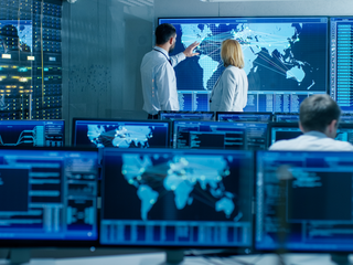 Analytics experts discussing in front of a big screen to determine solutions