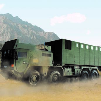 Close-up of a moving ballistic protected truck loaded with a ballistic protected TransProtec container. A barren hilly landscape can be seen in the background.