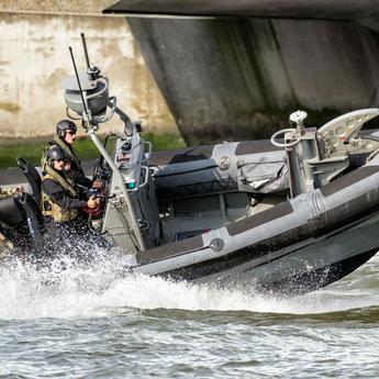 Military men navigating on a speed boat, monitoring coastal areas