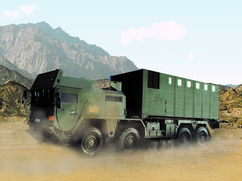 Close-up of a moving ballistic protected truck loaded with a ballistic protected TransProtec container. A barren hilly landscape can be seen in the background.