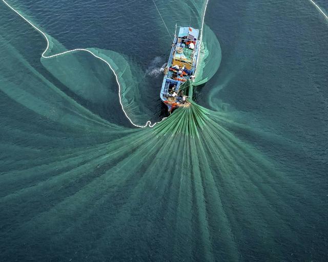 Fishing boat throwing a large net Fishing boat throwing a large net